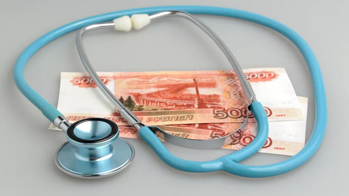 Две пятитысячные купюры на столе и сверху них медицинский стетоскоп Деньги врачам