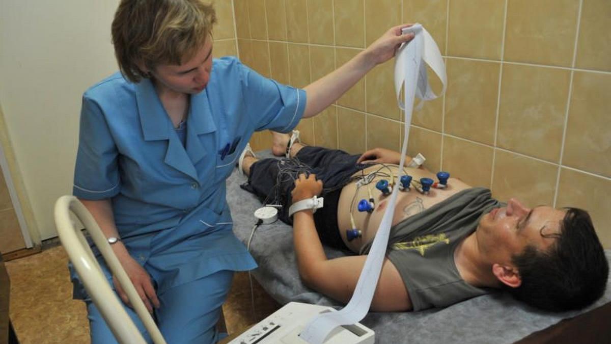 Врач снимает кардиограмму сердца В кабинете ЭКГ