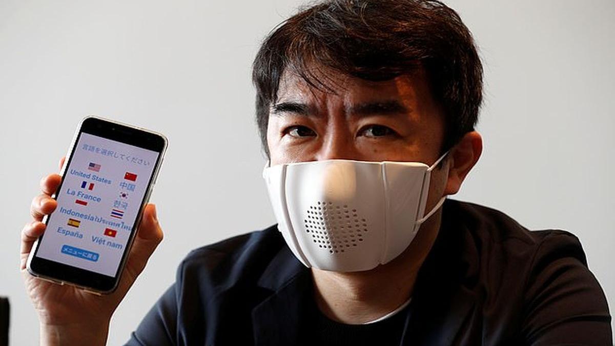 японец в “умной“ маске для лица и со смартфоном интеллектуальная маска для лица