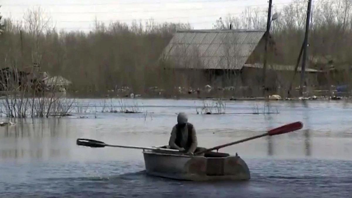 человек плывёт в лодке по улице во время паводка паводок в Якутске фото