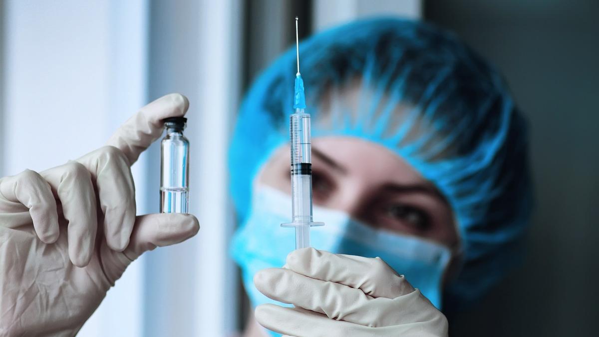 Врач с вакциной и шприцом в руках Врач