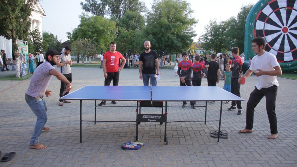 Молодые люди играют в настольный теннис во дворе Занятие настольным теннисом